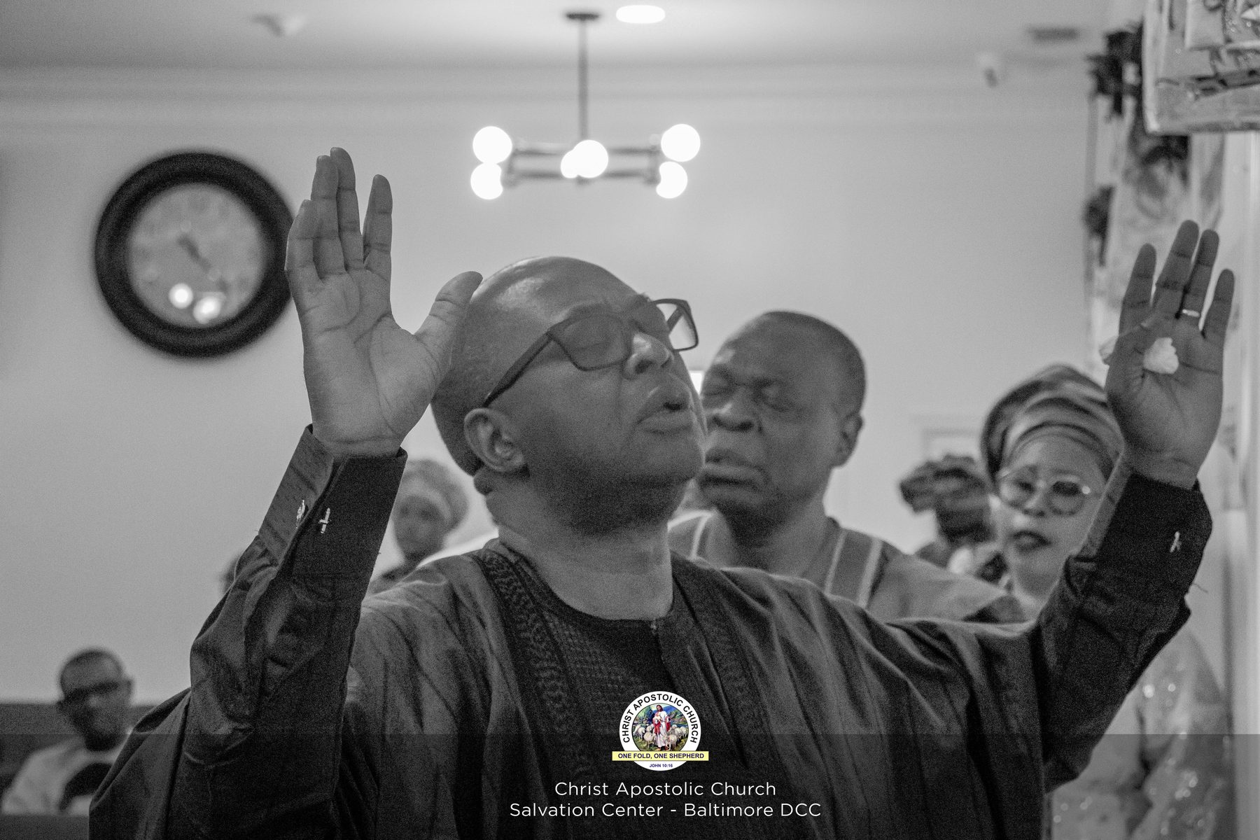Black and white photo of worshippers with raised hands